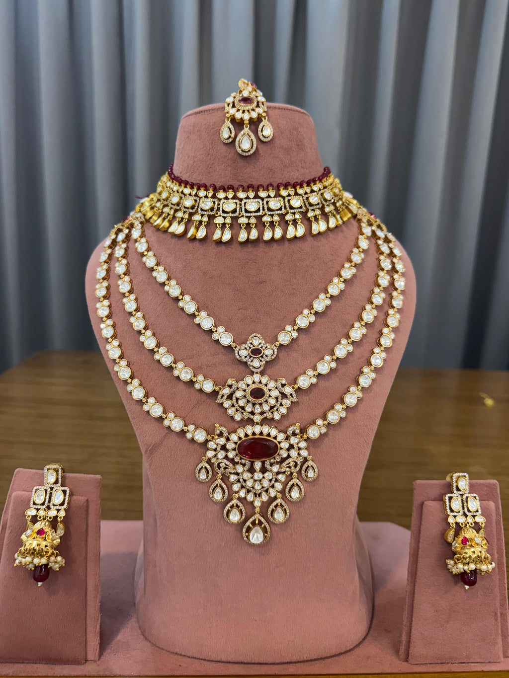 Ruby red kundan bridal set with choker, 3-line long haar, earrings and maang tikka on a mannequin