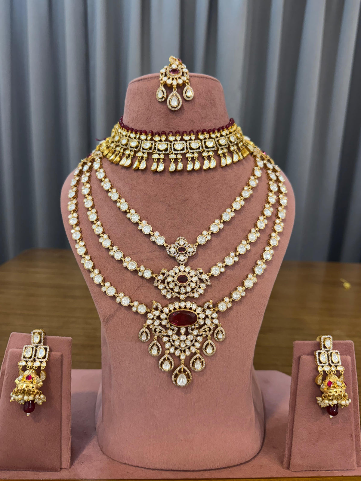 Ruby red kundan bridal set with choker, 3-line long haar, earrings and maang tikka on a mannequin
