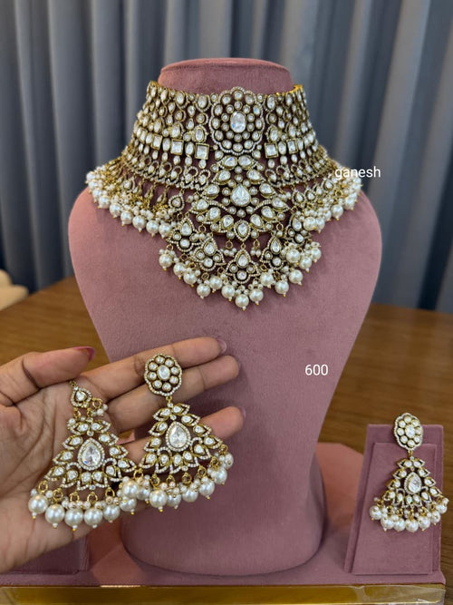 Ornate necklace and earrings set on a mannequin bust with a blurred background