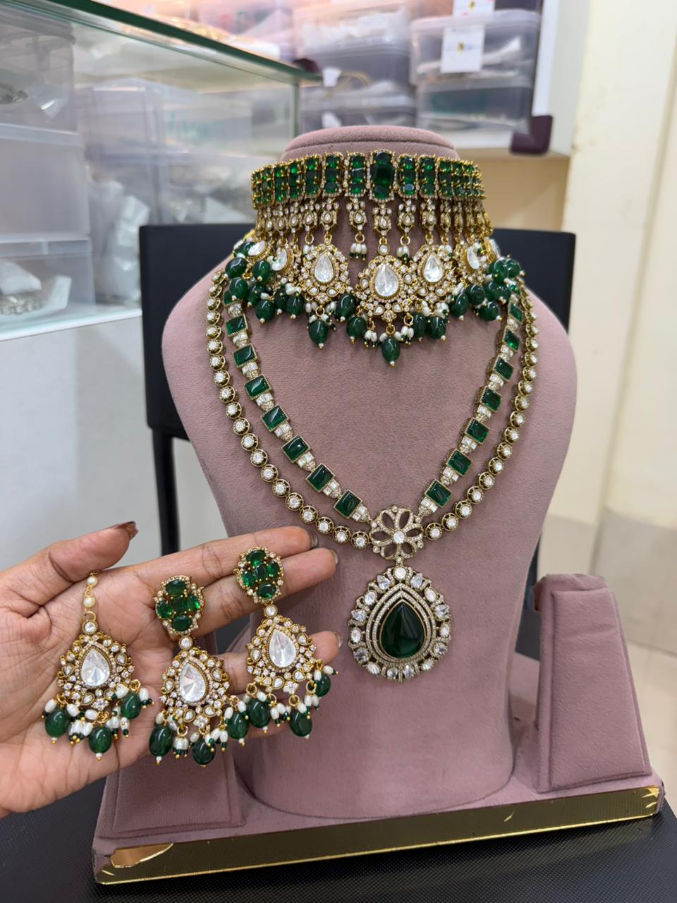 Green and gold bridal  jewelry set on a mannequin and held by a hand